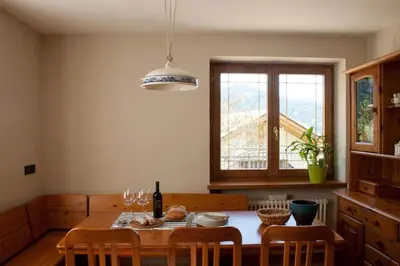 a kitchen with a table with chairs and a window at Casa Dolci by Sunhome Fiemme in Tesero