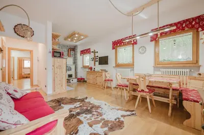 a living room with a table and a dining room at I Folli di Alleghe Apartment - Parking & Wi-Fi in Caprile