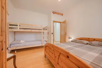 a bedroom with two bunk beds and a chair at I Folli di Alleghe Apartment - Parking & Wi-Fi in Caprile