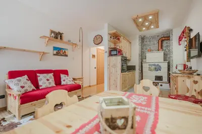 a living room with a red couch and a table at I Folli di Alleghe Apartment - Parking & Wi-Fi in Caprile