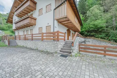a house with a stone wall and a fence at I Folli di Alleghe Apartment - Parking & Wi-Fi in Caprile
