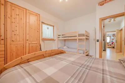 a bedroom with a large bed and bunk beds at I Folli di Alleghe Apartment - Parking & Wi-Fi in Caprile