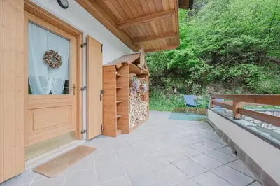 a porch with a wooden door and a chair at I Folli di Alleghe Apartment - Parking & Wi-Fi in Caprile