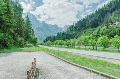 a road with a bench on the side of a mountain at I Folli di Alleghe Apartment - Parking & Wi-Fi in Caprile