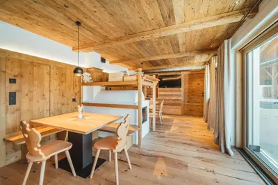 a room with a wooden ceiling and a table and chairs at Kuenzerhof Apartments in Braies
