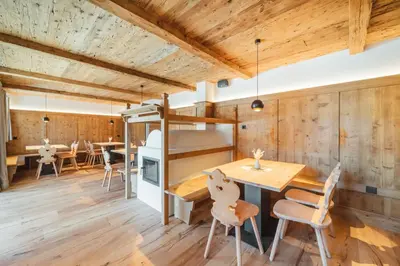 a kitchen and dining room with wooden walls and a table and chairs at Kuenzerhof Apartments in Braies