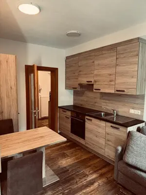 a kitchen with wooden cabinets and a table with a sink at Wohnung in Olang, perfekte Unterkunft für Olympia in Valdaora di Sotto