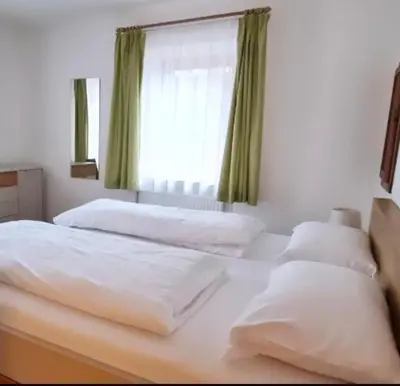 a bedroom with two beds and a chair and two windows at Wohnung in Olang, perfekte Unterkunft für Olympia in Valdaora di Sotto