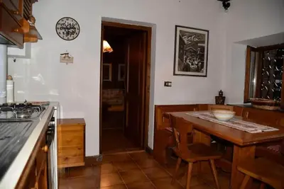 a kitchen with a counter and a wooden table at Casa Via Soia in Canale dʼAgordo