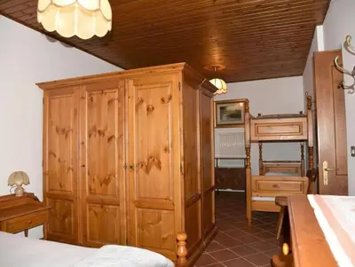 a bedroom with a wooden cabinet and a bed at Casa Via Soia in Canale dʼAgordo