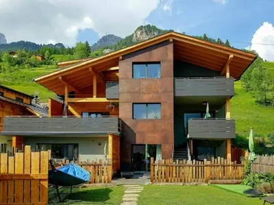 a house with a wooden fence in front of it at Family-Friendly Mountain Home In The Dolomites in Campitello di Fassa