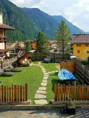 a backyard with a stone path in the grass at Family-Friendly Mountain Home In The Dolomites in Campitello di Fassa