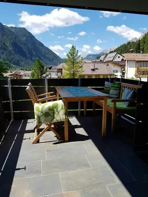 a wooden table and chairs on a balcony with mountains at Apartment In The Dolomites With Panoramic View in Campitello di Fassa