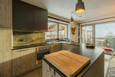 a kitchen with wooden cabinets and a large window at Apartment In The Dolomites With Panoramic View in Campitello di Fassa