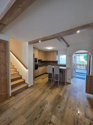 an open kitchen and living room with wooden floors at Appartamento La Meridiana in Tonadico