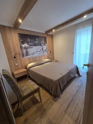 a bedroom with a large bed and a chair at Appartamento La Meridiana in Tonadico