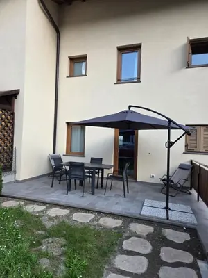 a patio with a table and chairs and an umbrella at Appartamento La Meridiana in Tonadico