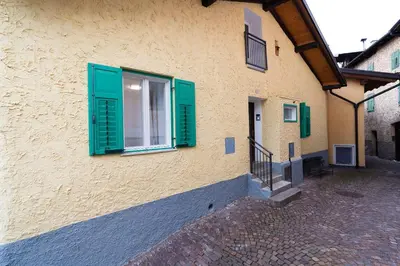 a building with green shutters on the side of it at La bottega del sarto in Grumes