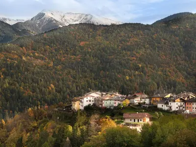 a town in the mountains with trees and houses at La bottega del sarto in Grumes