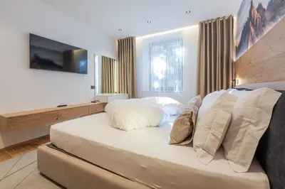 a bed covered in white sheets and pillows at Apartament Tre Cime in San Sigismondo