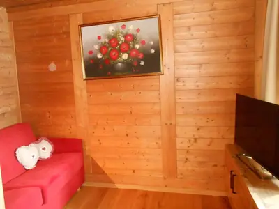 a room with a red couch and a christmas tree at Ferienwohnung Lamprechtsburg in Brunico
