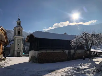 a church with a clock tower in the snow at Ferienwohnung Lamprechtsburg in Brunico