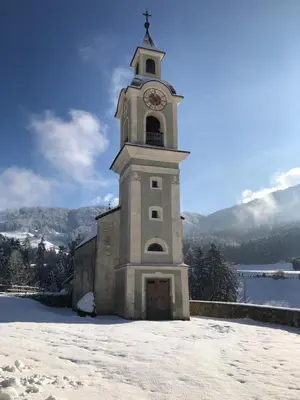 a tall tower with a clock on it in the snow at Ferienwohnung Lamprechtsburg in Brunico
