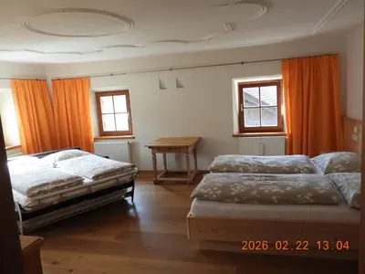 a bedroom with two beds and a table and windows at Hanslmoar Hof in Colli in Pusteria