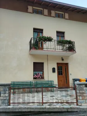 a building with a bench and a balcony with flowers at La Casa di Anna in Agordo