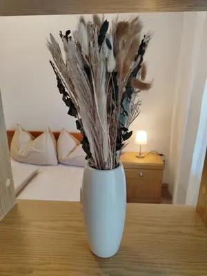 a white vase sitting on a table with flowers at Bergblick 33 in Plaus