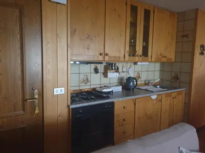 a kitchen with a black stove and wooden cabinets at Dolomite Nest in Colle Santa Lucia