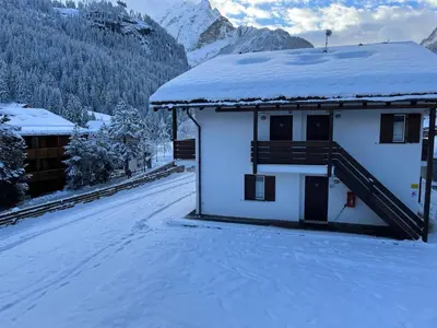 a house with a snow covered roof in the mountains at Bilocale Casa Canazei in Alba di Canazei