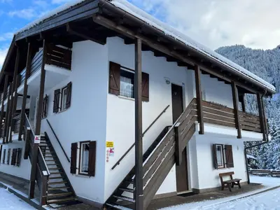 a house with a staircase in the snow at Bilocale Casa Canazei in Alba di Canazei