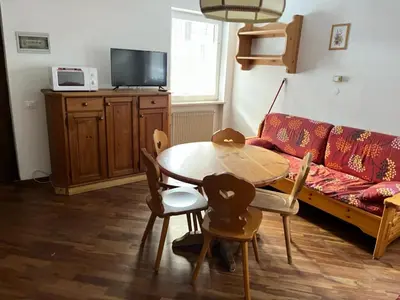 a living room with a table and a couch at Bilocale Casa Canazei in Alba di Canazei
