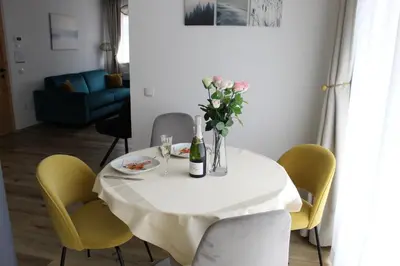 a white table with a vase of flowers and chairs at Fox Appartements in San Lorenzo di Sebato