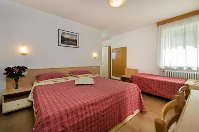a hotel room with two beds with red sheets at Garni Ciamorc in Canazei