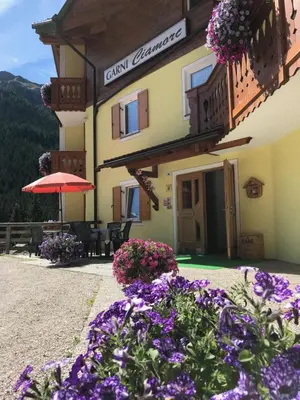 a building with purple flowers in front of it at Garni Ciamorc in Canazei