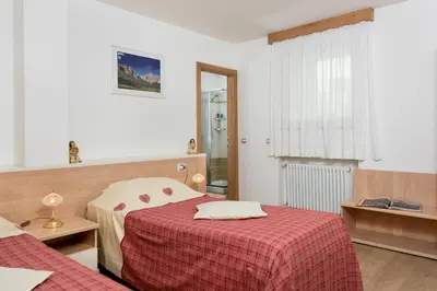 a bedroom with two beds and a red blanket at Garni Ciamorc in Canazei