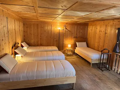 a room with three beds in a wooden cabin at Vicinanza d'Andraz in Andraz