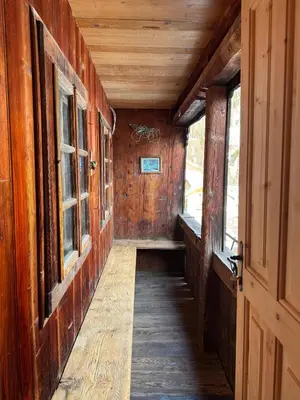 an empty hallway in a wooden cabin with windows at Vicinanza d'Andraz in Andraz