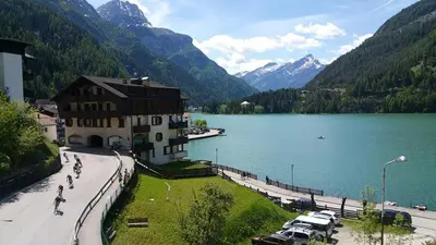 a large building next to a lake with mountains at Appartamento Italia in Alleghe