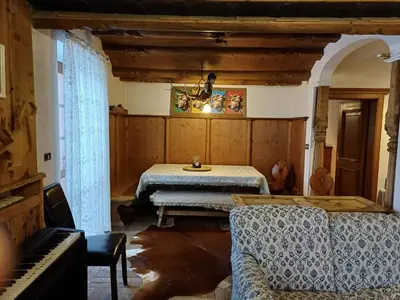 a living room with a table and a piano at Sweet Home Cortina in Cortina dʼAmpezzo