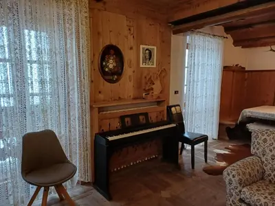 a living room with a piano and a chair at Sweet Home Cortina in Cortina dʼAmpezzo