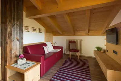 a living room with a red couch and a tv at Appartamenti Ciasa Murin in San Cassiano