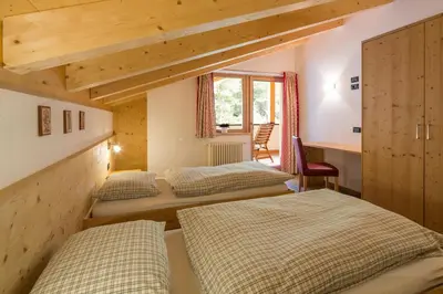 a bedroom with three beds and a desk and a window at Appartamenti Ciasa Murin in San Cassiano