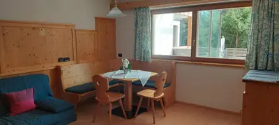 a kitchen with a table and chairs and a couch at Appartamenti Ciasa Murin in San Cassiano