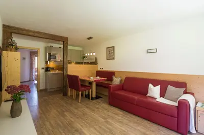 a living room with a red couch and a table at Appartamenti Ciasa Murin in San Cassiano