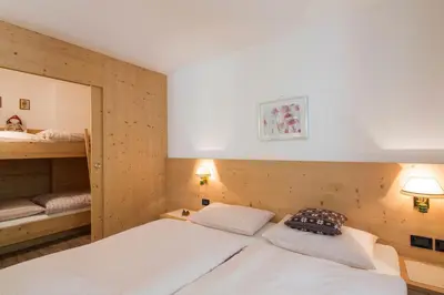 a bedroom with two beds and a bunk bed at Appartamenti Ciasa Murin in San Cassiano