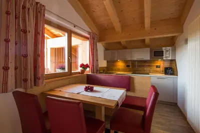 a small kitchen with a wooden table and chairs at Appartamenti Ciasa Murin in San Cassiano