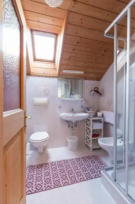 a bathroom with a sink and a toilet and a window at Ciasa Rü in San Cassiano